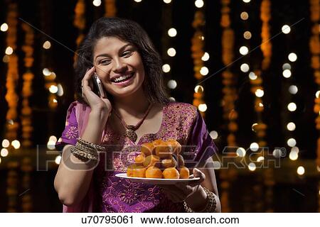 Woman with a plate of sweets talking on mobile phone View Large Photo Image Stock Image - Woman with a plate of sweets talking on mobile phone. Fotosearch