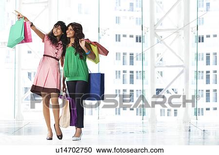 Stock Image - Women looking at something while shopping . Fotosearch