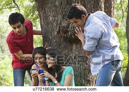 Women sharing messages while men peeking from behind View Large Photo Image Stock Photo - Women sharing messages while men peeking from behind . Fotosearch