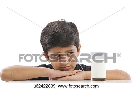 Young boy looking at a glass of milk View Large Photo Image Stock Photo - Young boy looking at a glass of milk . Fotosearch