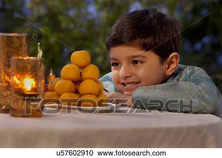 Stock Image - Young boy looking at laddoos . Fotosearch