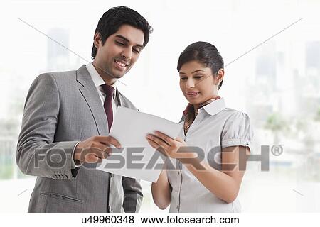 Young business colleagues looking at file in office View Large Photo Image Stock Photo - Young business colleagues looking at file in office . Fotosearch