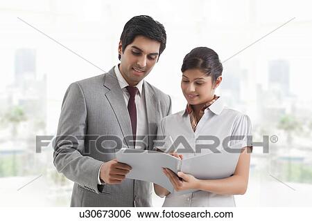 Stock Photograph - Young business colleagues looking at document in office . Fotosearch