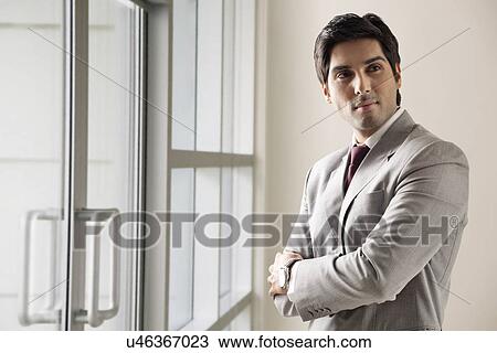 Young business man standing with arms crossed View Large Photo Image Stock Image - Young business man standing with arms crossed . Fotosearch