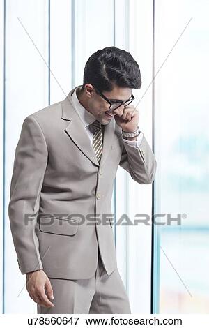 Young businessman answering mobile phone in office View Large Photo Image Stock Photo - Young businessman answering mobile phone in office. Fotosearch