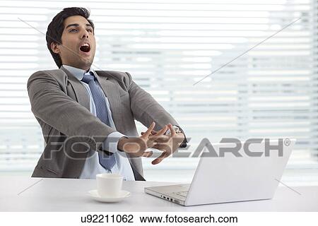 Young businessman stretching while at work View Large Photo Image Stock Image - Young businessman stretching while at work . Fotosearch
