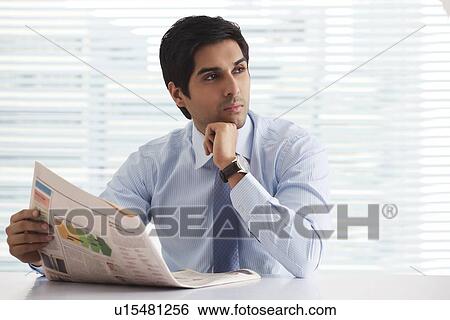 Young businessman thinking with newspaper at office View Large Photo Image Stock Photograph - Young businessman thinking with newspaper at office . Fotosearch