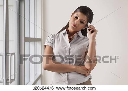 Stock Photograph - Young businesswoman in deep thought with mobile phone . Fotosearch