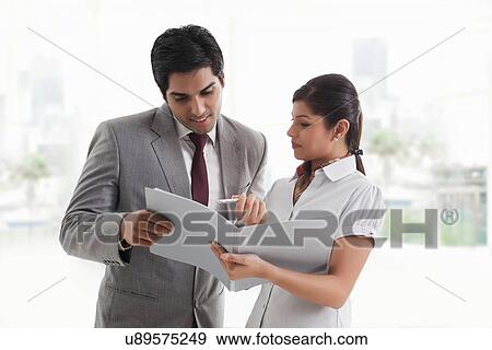 Stock Photo - Young businesswoman showing document to businessman in office . Fotosearch