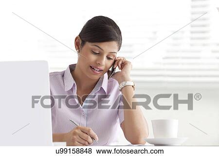 Young businesswoman writing white using cell phone View Large Photo Image Stock Photo - Young businesswoman writing white using cell phone . Fotosearch