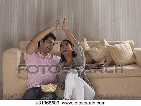 Young couple giving high-five to each other while watching TV View Large Photo Image Stock Photo - Young couple giving high-five to each other while watching TV . Fotosearch