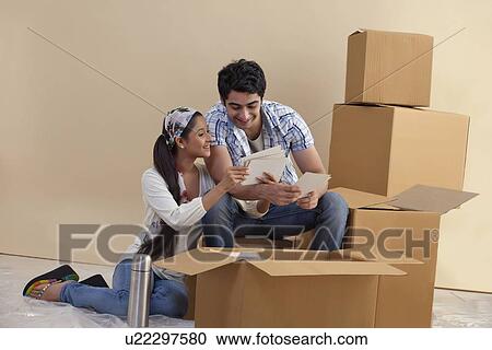 Young couple looking at photographs together at home View Large Photo Image Stock Image - Young couple looking at photographs together at home . Fotosearch
