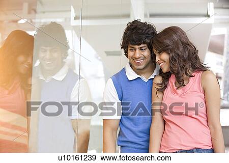 Stock Photo - Young couple looking at window display together . Fotosearch