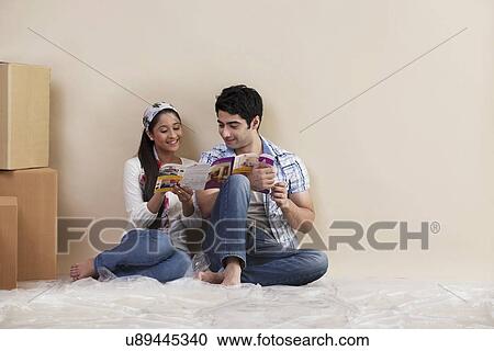 Stock Image - Young couple reading magazine together at their new home . Fotosearch