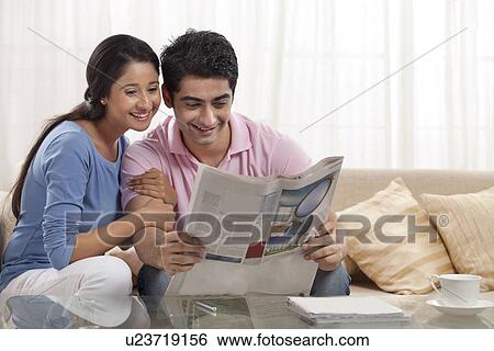 Stock Photograph - Young couple reading newspaper together at home . Fotosearch