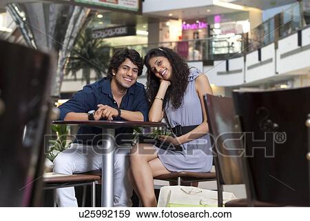 Young couple sitting together in shopping mall View Large Photo Image Stock Photo - Young couple sitting together in shopping mall . Fotosearch