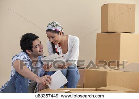 Young couple smiling while looking at photographs View Large Photo Image Stock Photo - Young couple smiling while looking at photographs . Fotosearch