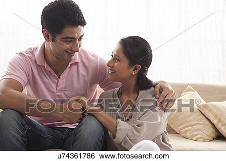 Young couple smiling while looking at each other View Large Photo Image Stock Photograph - Young couple smiling while looking at each other . Fotosearch