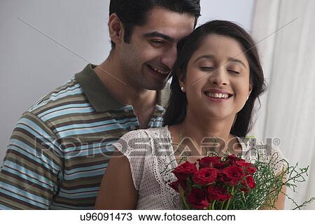 Stock Image - Young couple together with bouquet at home . Fotosearch