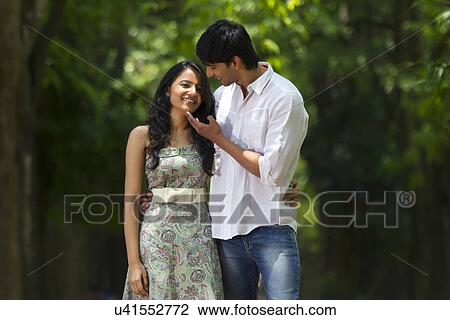 Stock Image - Young couple walking together in a park . Fotosearch