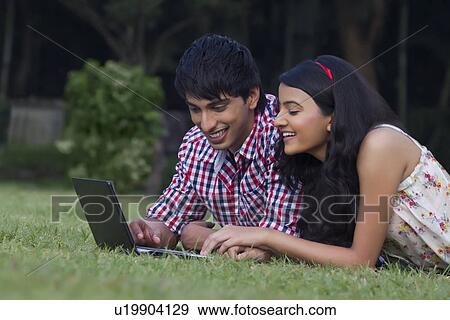 Young couple with a laptop in a park View Large Photo Image Stock Photo - Young couple with a laptop in a park . Fotosearch