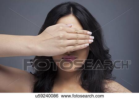 Young female covering eyes her with hand over colored background View Large Photo Image Stock Photograph - Young female covering eyes her with hand over colored background . Fotosearch