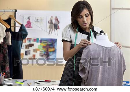 Picture - Young female designer fixing dress on mannequin . Fotosearch