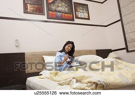 Young female having morning tea in bed View Large Photo Image Stock Photograph - Young female having morning tea in bed . Fotosearch