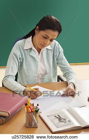 Stock Photo - Young female teacher writing on paper . Fotosearch