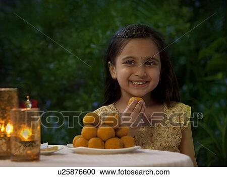 Young girl eating a laddoo View Large Photo Image Stock Image - Young girl eating a laddoo . Fotosearch