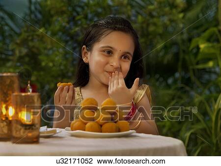 Young girl eating a laddoo View Large Photo Image Stock Image - Young girl eating a laddoo . Fotosearch