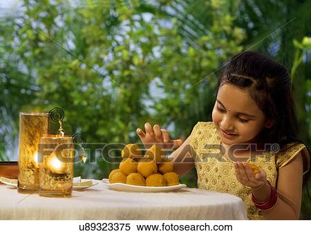 Young girl holding a laddoo View Large Photo Image Stock Photography - Young girl holding a laddoo . Fotosearch
