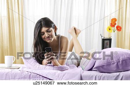 Young girl with a mobile phone in bed View Large Photo Image Stock Photo - Young girl with a mobile phone in bed . Fotosearch