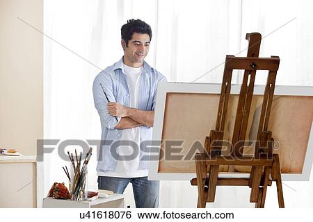Young handsome man painting at an easel View Large Photo Image Stock Photograph - Young handsome man painting at an easel . Fotosearch