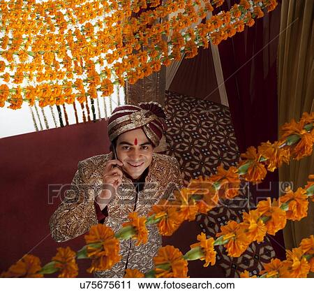 Young Indian bridegroom talking on mobile phone while looking up View Large Photo Image Stock Image - Young Indian bridegroom talking on mobile phone while looking up . Fotosearch