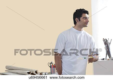 Young male artist holding paintbrush and palette View Large Photo Image Stock Image - Young male artist holding paintbrush and palette . Fotosearch