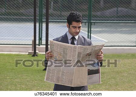 Young male corporate business executive reading newspaper in a tennis court View Large Photo Image Stock Image - Young male corporate business executive reading newspaper in a tennis court . Fotosearch