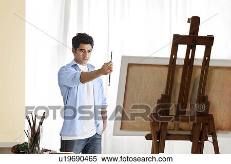 Stock Photography - Young male painter painting in art studio . Fotosearch