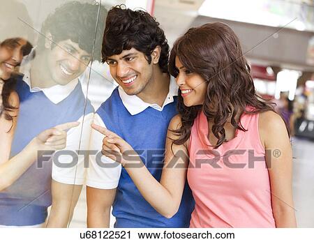 Stock Image - Young man and woman smiling while window shopping . Fotosearch