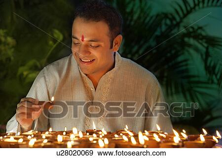 Stock Photo - Young man holding a diya . Fotosearch