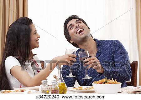 Young man laughing while having wine with his girlfriend at restaurant View Large Photo Image Stock Image - Young man laughing while having wine with his girlfriend at restaurant . Fotosearch