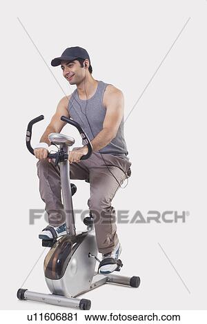 Stock Image - Young man listening music while exercising over white background . Fotosearch