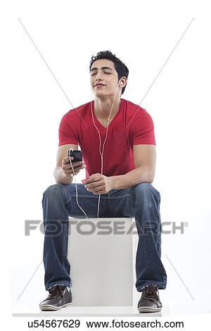 Young man listening to music through earphones View Large Photo Image Stock Photo - Young man listening to music through earphones . Fotosearch