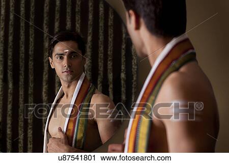 Young man looking at self in mirror View Large Photo Image Stock Image - Young man looking at self in mirror . Fotosearch