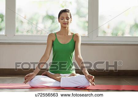 Stock Image - Young man meditating in morning on exercise mat . Fotosearch