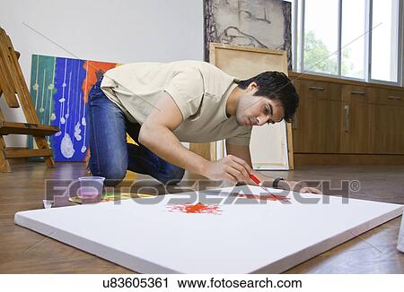 Young man painting on an artist's canvas at art studio View Large Photo Image Stock Image - Young man painting on an artist's canvas at art studio . Fotosearch