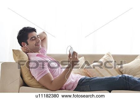 Young man relaxing while listening to music View Large Photo Image Stock Image - Young man relaxing while listening to music . Fotosearch