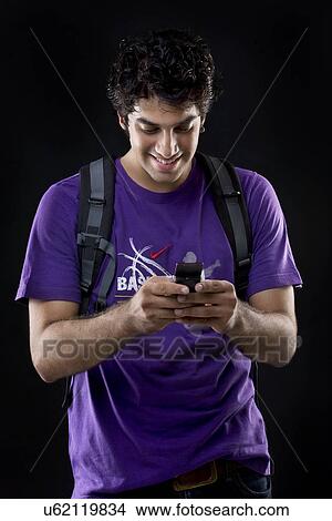 Young man sending a text message View Large Photo Image Picture - Young man sending a text message . Fotosearch
