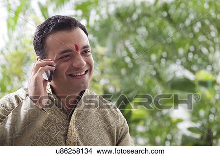 Young man talking on a mobile phone View Large Photo Image Picture - Young man talking on a mobile phone . Fotosearch