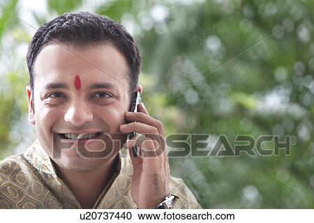 Young man talking on a mobile phone View Large Photo Image Stock Image - Young man talking on a mobile phone . Fotosearch